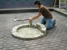 Laying brick stones to build a fire pit.