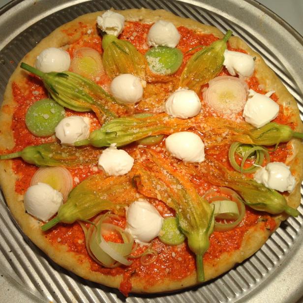 Red pepper pesto, leek and squash blossom pizza ready for oven Red pepper pesto, leek and squash blossom pizza ready for oven