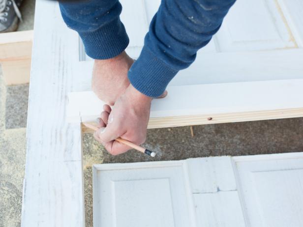 Measure and mark the opening of the newly cut door directly to the strip of 1’ x 3’ x 6’ lumber, allowing enough space for a 1” overhang on both sides to accommodate a decorative ledge.