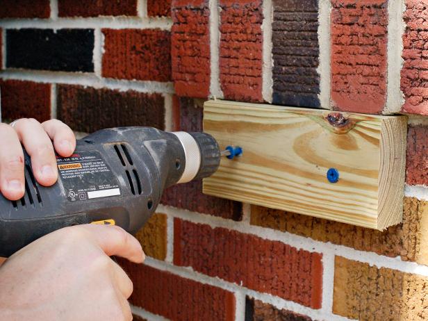 Before affixing window box to wall or wood used to level wall with window, screw in anchors which will serve to better keep window box connected to wall.