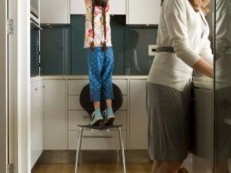 Girl reaching for cookie jar in kitchen with mother