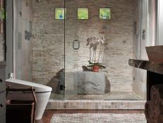 Luxury means being able to do yoga poses in your shower â   at least for one of designer Susan Fredman's clients. She delivered not only a large space but also a dramatic boulder rock for seating. Earth tones, textured tiles, natural light and a steam shower complete this soothing, masculine space.