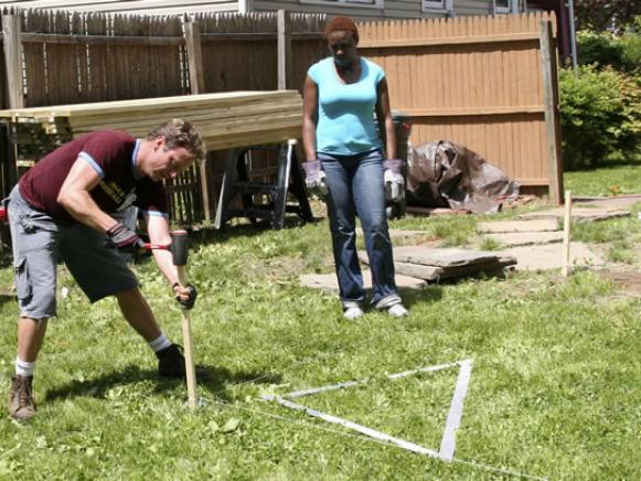 Man measuring ground for base of the deck.