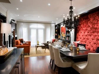 A black crystal chandelier against a red backdrop adds a dramatic touch to this dining room. Recessed lighting brightens up the rest of the space.