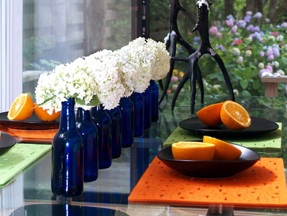 Table Setting With a Row of White Flowers in Dark Blue Bottles