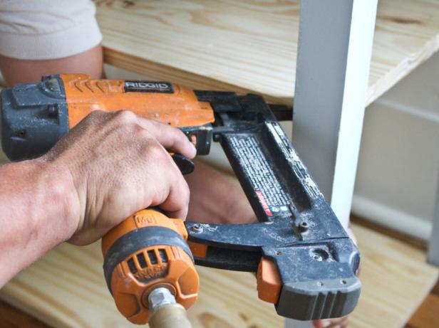 Man using nail gun to secure shelf.