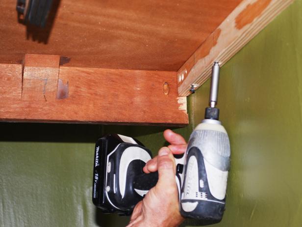 Slide buffet into place laying bottom of table on top of cleat. Fasten table to cleat by drilling wood screw through cleat and into table from underneath using drill.