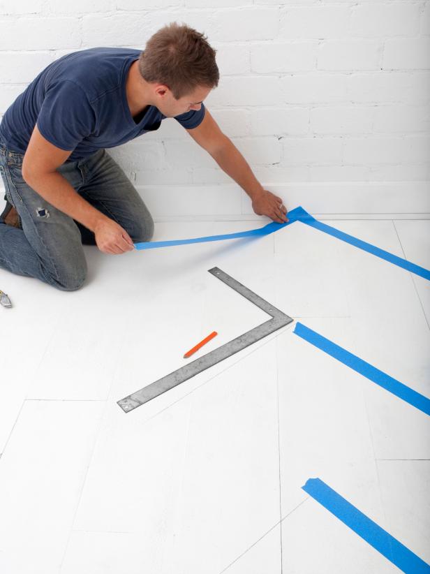 Blue painter's tape is used to prep a floor for a coat of paint
