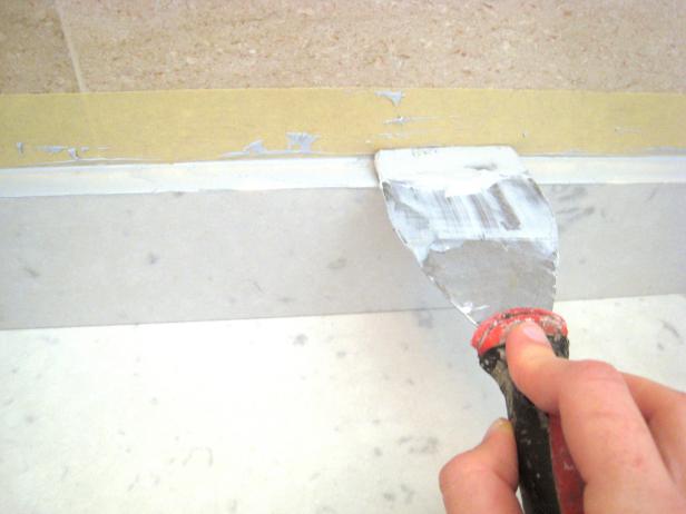 Tape off the wall behind the backsplash to ensure a straight, even line for the caulk. Painter's tape is recommended for this.