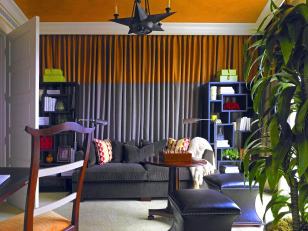 Two-toned curtains add texture behind the gray sofa in this eclectic family room. Modular book shelves, a star-shaped light fixture and nailhead ottomans create a relaxed space full of character and color.