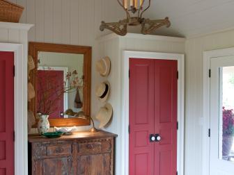 White Mudroom With Two Closets With Red Doors and Antique Dresser