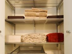 Closet With Metal Shelving Holding Towels, Bed Linens and a Pillow