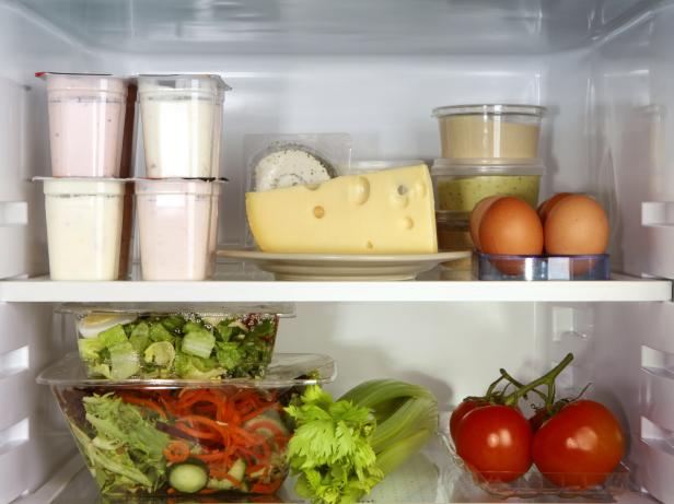 Open refrigerator door containing produce and other food items.