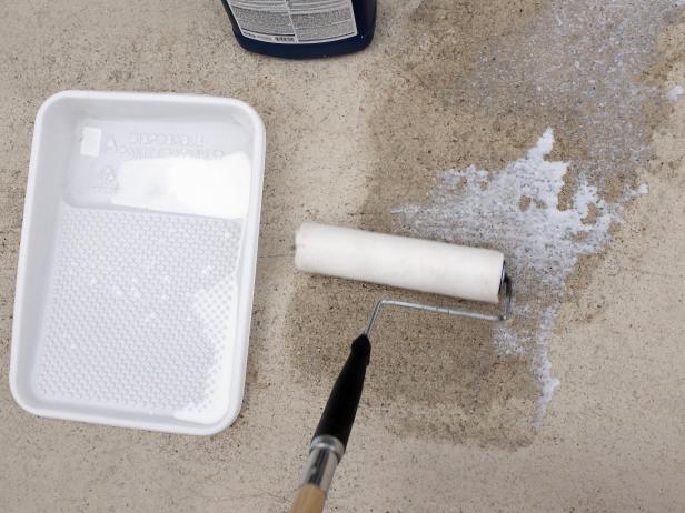 Waterproof sealer in a paint pan with roller, on exterior concrete.