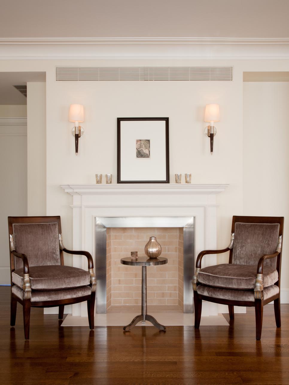 Brick Fireplace Flanked by Velvet Chairs & Sconces