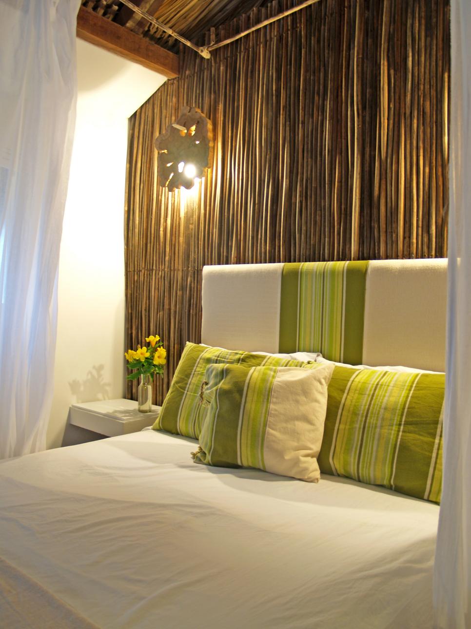 White Bed With Green Striped Headboard Against Rattan Wall