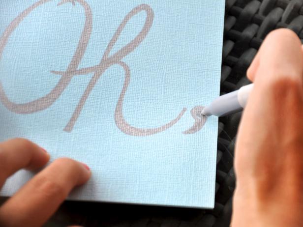 The next step in making the joy card is to carefully write "Oh," in large cursive letters.
