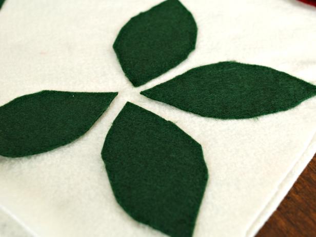 Apply fabric glue to the back of each leaf and stick it to the cream felt in the desired position.