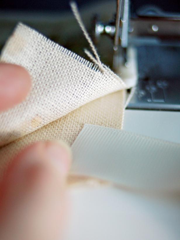 Separate the freezer paper from the linen. Assemble pockets with right sides facing out. Cut 50 lengths of grosgrain ribbon to approximately eight inches each. Insert ribbon between two pieces of linen in the upper right corner.