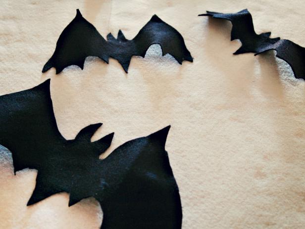 Spooky black fabric bats are attached to a Halloween applique pillow.