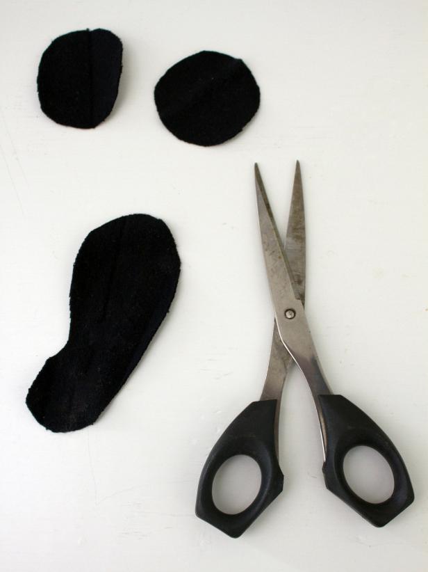 Cutting out eyes and a mouth for a DIY Halloween ghost is simple and fun.