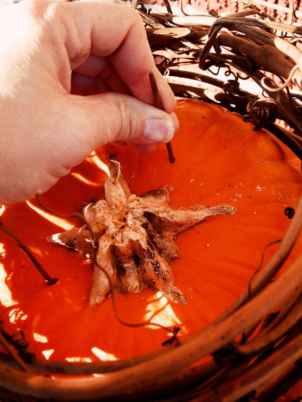 Insert three trimmed pieces of wired stem into top of large pumpkin leaving half of the wire exposed.