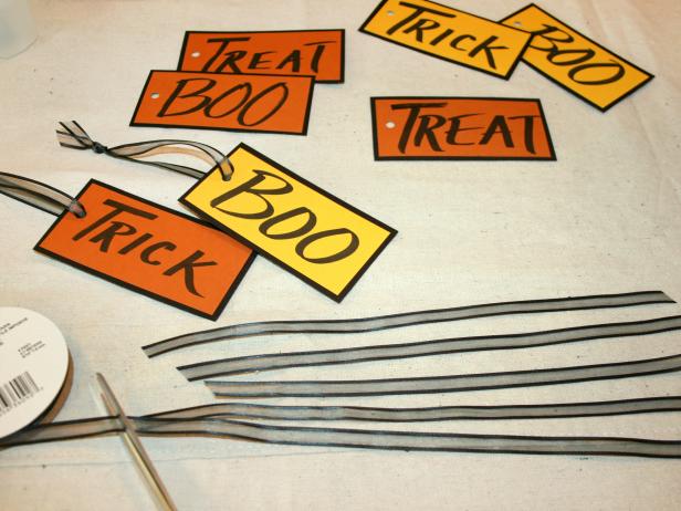 Cut ribbon into 10-inch lengths and thread ribbon through the paper words that you'll hang on the Halloween centerpiece.