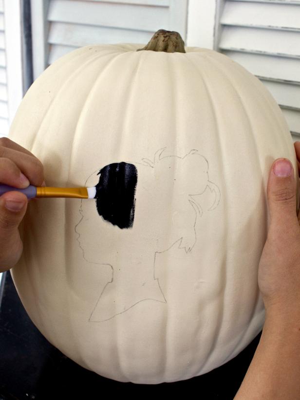 Remove the paper silhouette and stick pins, then use a flat-edged paintbrush to fill in the outline with black acrylic paint.