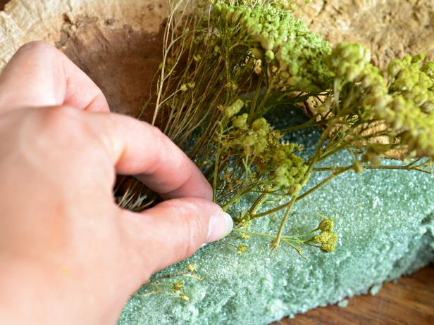 Tuck flower in desired location, wrap florist wire around wreath form and twist ends together to secure in place. Some flowers may have strong enough stems to stick directly into foam.
