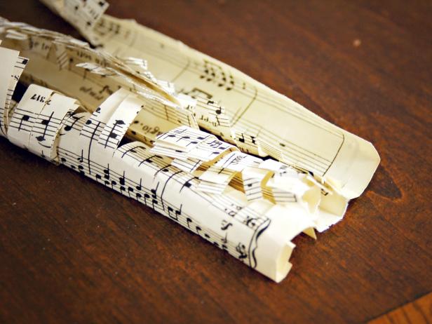 This fringed sheet music strip is being unrolled and separated to glue to a foam Christmas tree.