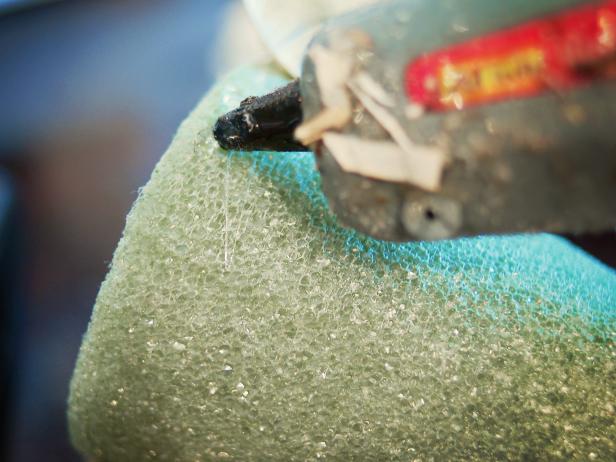 Hot glue is applied to this foam Christmas tree with a hot glue gun.