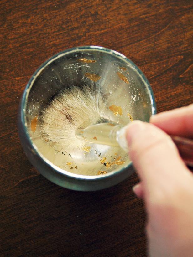 Silver leaf is smoothed in the interior of this glass votive with a brush.