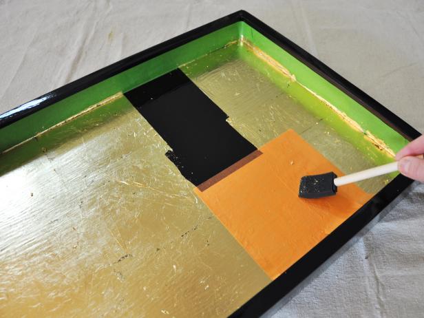 Once the entire surface is covered with gold leaf, brush away loose particles with a foam brush.