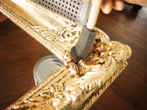 In a well-ventilated area, apply dark walnut wood stain to a small section of frame using a one-inch foam brush, working the stain into molded details.