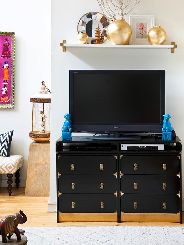 A black console is just as much the focal point as the television in this eclectic living room. A sprinkling of bohemian collectibles and printed textiles complete the living space.