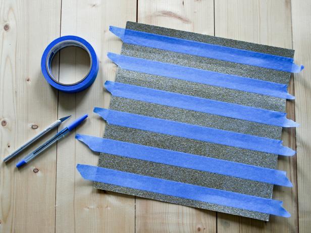 On paper's glittered side, place painter's tape along the center of each scored line. Paint exposed paper with mint-green paint