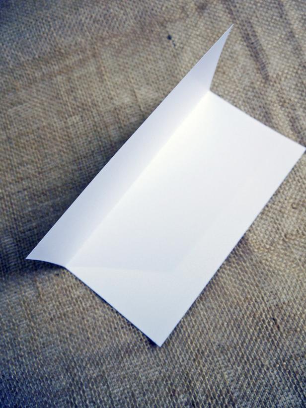 Start with a square of white card stock. Fold in half lengthwise, then fold in half again, widthwise. Then, fold across to create a triangle.