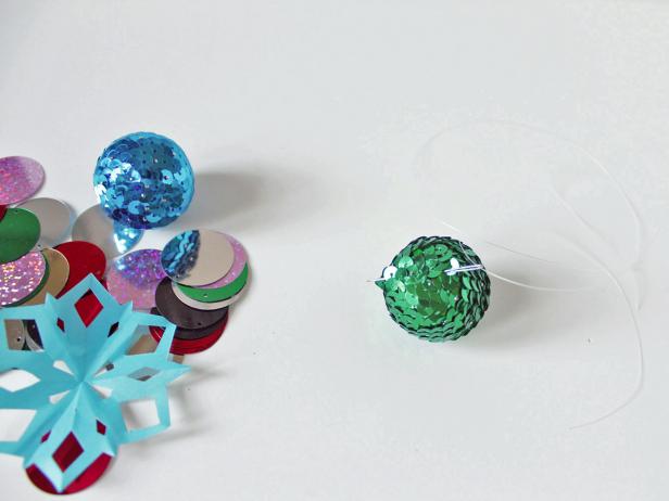 To create your holiday garland, string a 30-inch piece of monofilament onto the sewing needle. Start with the sequin ball by threading the monofilament through a top section of it.