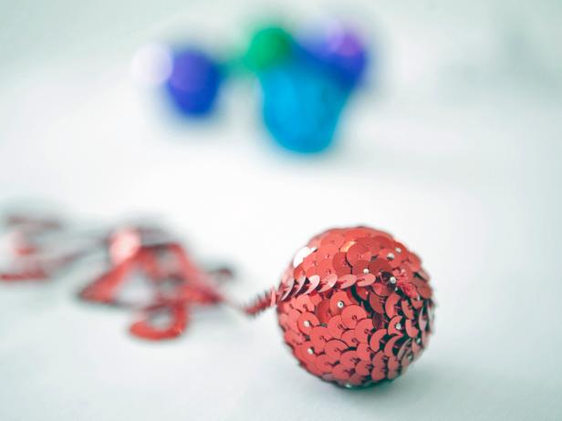 Keep wrapping and pinning until the whole ball is covered. Place a final pin at the bottom of the ball and cut off the extra trim.