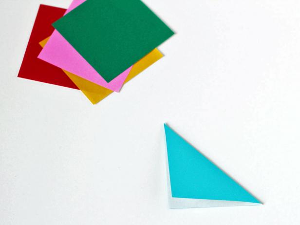 Start making the snowflakes by folding a sheet of paper into a triangle.