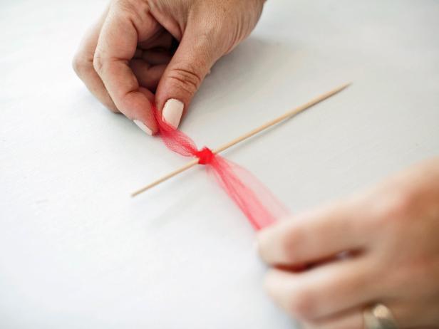 Cut the tulle into 1-inch strips. Tie the strips around the top of plain, wooden stirrers.