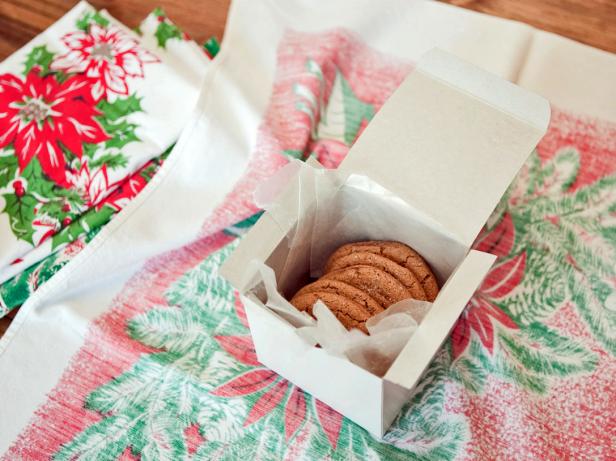 Once the towel is complete, use it as functional wrapping paper for homemade cookies. Fill a white pastry box with a wax paper liner and a pile of homemade cookies.