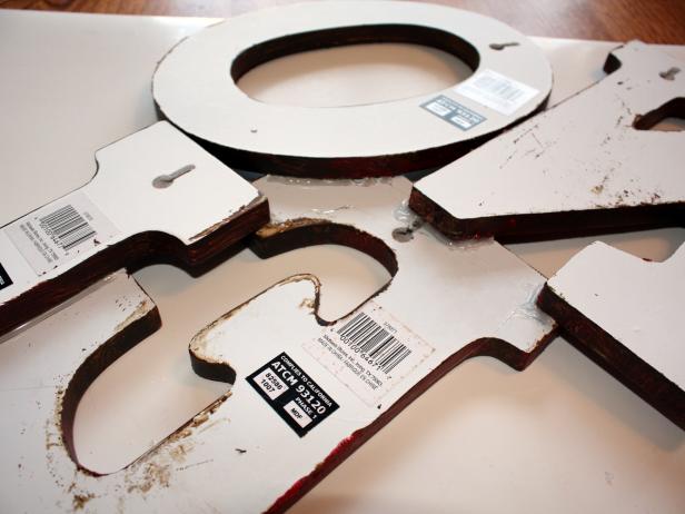 When your letters are completely dry, arrange them how you want on a piece of cardboard. Place another piece of cardboard on the front of the letters to help flip them over. Take your glue gun, and fill all the gaps with hot glue. When your glue is set, simply place a few strategic nails on your wall and hang the sign.