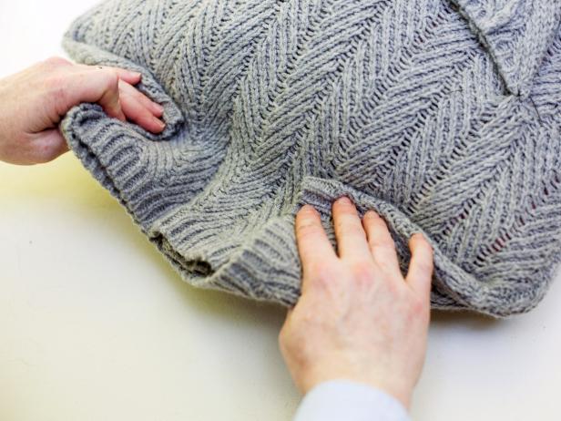 Folding a sweater to the back of a pillow insert.
