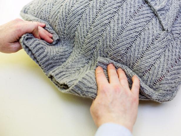 Folding a sweater to the back of a pillow insert. 