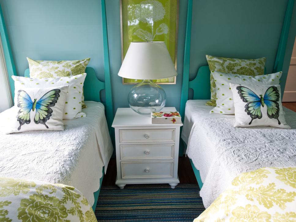 Blue Bedroom With Twin Beds, White End Table and Transparent Lamp