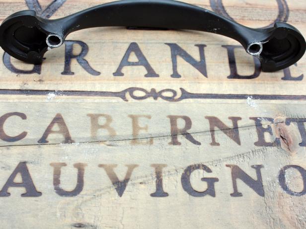 Touch the chalked handles to the sides of your crate, one at a time, to create white marks where you'll need to drill. Once the chalk is in place, reinforce the mark with a pen. Then drill holes using a drill bit the same size as your hardware screws.