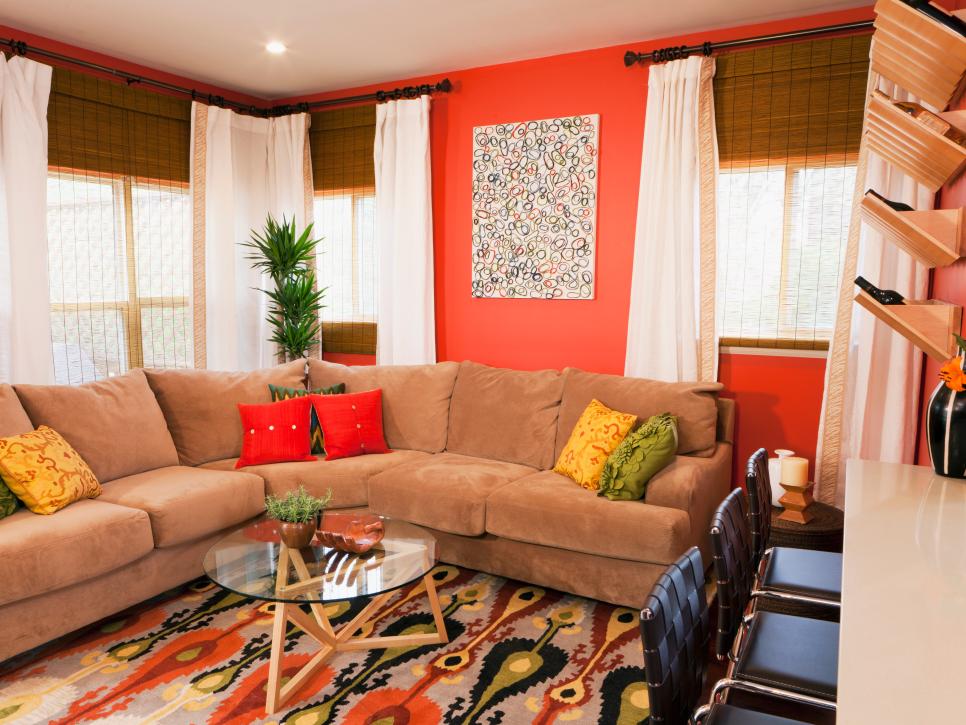 Living Room With Bamboo Shades, White Drapes and a Brown Sectional Sofa With Fiery Orange Walls
