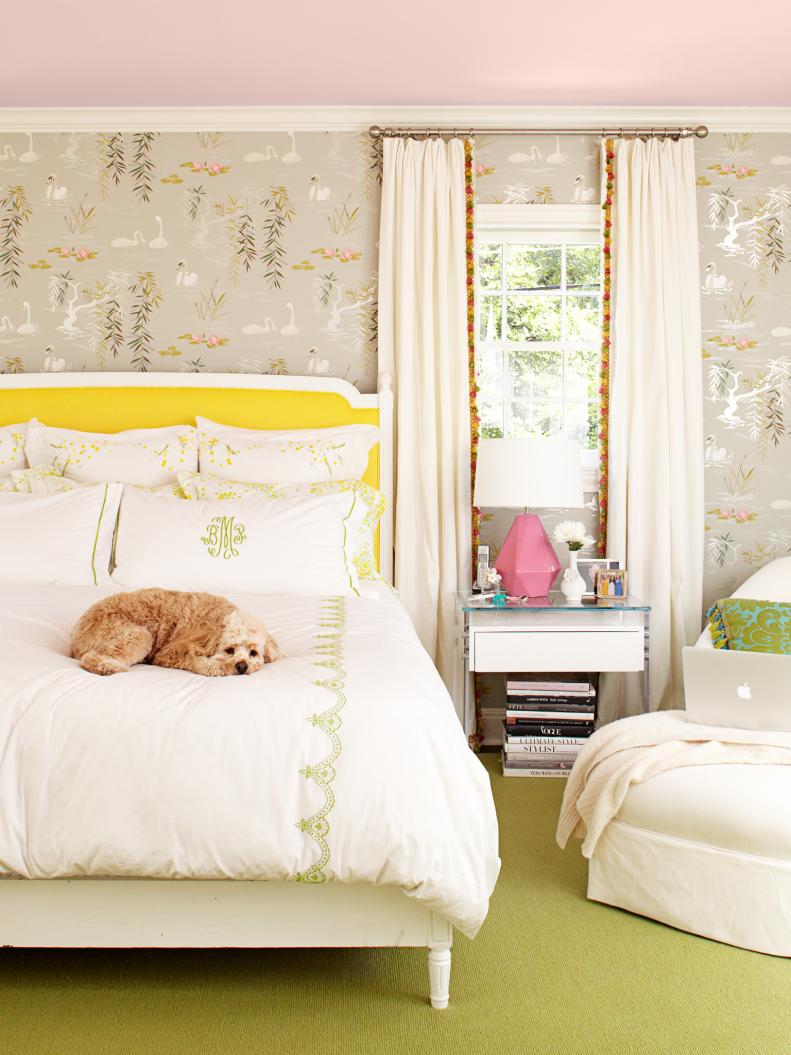Bedroom with printed wallpaper and white monogrammed bedding.