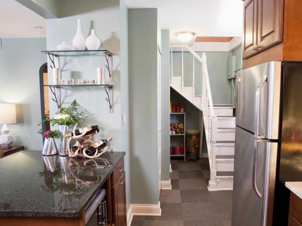 Light Blue Kitchen With Peninsula Next to White Staircase and Storage 